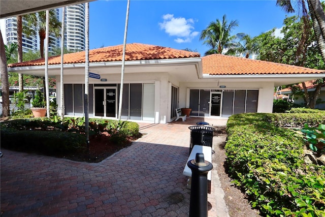 rear view of house featuring stucco siding and a tiled roof