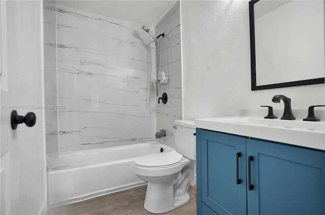 bathroom featuring a textured wall, toilet, shower / bath combination, wood finished floors, and vanity