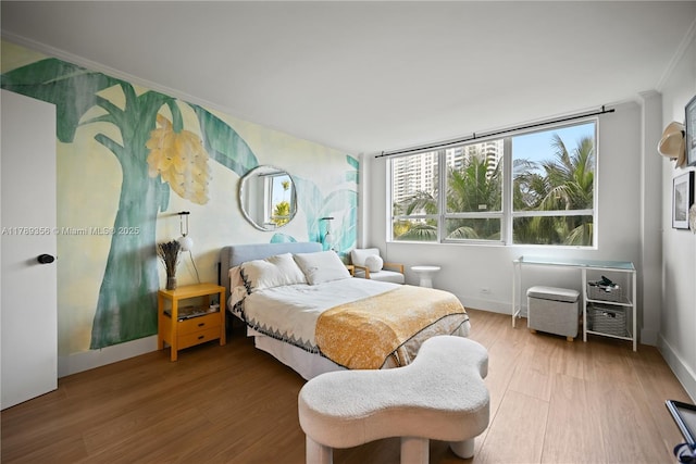 bedroom with wood finished floors, ornamental molding, and baseboards