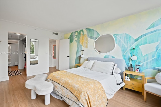 bedroom with wood finished floors, visible vents, crown molding, and baseboards