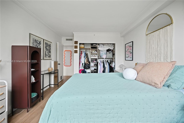 bedroom featuring ornamental molding, a closet, visible vents, and wood finished floors