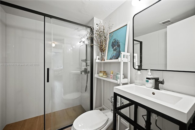 full bathroom with toilet, a sink, visible vents, and a shower stall