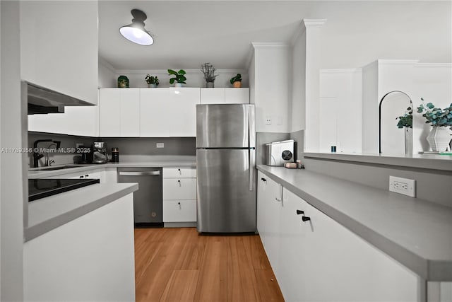 kitchen with a sink, stainless steel appliances, light countertops, ornamental molding, and white cabinets