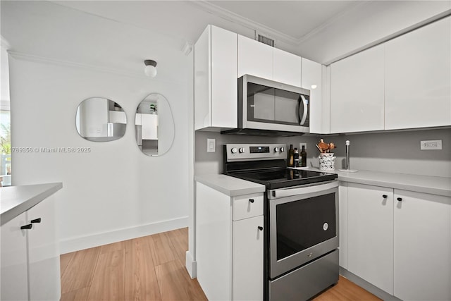 kitchen with appliances with stainless steel finishes, white cabinetry, crown molding, and light countertops