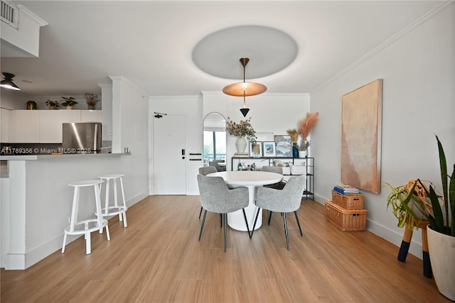 dining room featuring visible vents, ornamental molding, light wood finished floors, and baseboards