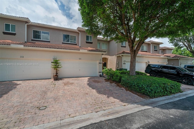 view of front of house featuring a tile roof, driveway, a garage, and stucco siding