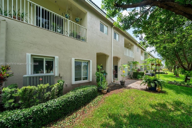 exterior space featuring stucco siding, a yard, and central air condition unit