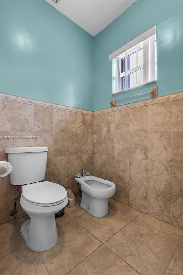 19404 NW 79th Ct, Hialeah, FL 33015 - bathroom featuring toilet, a bidet, tile walls, a wainscoted wall, and tile patterned floors