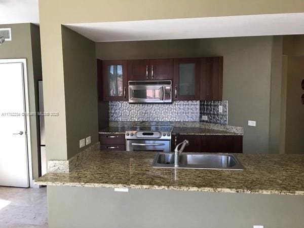 kitchen with stone counters, stainless steel appliances, decorative backsplash, and a sink