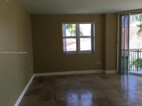 spare room with a wealth of natural light and baseboards