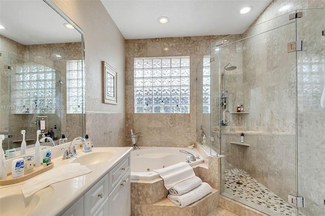 bathroom with tile walls, a stall shower, vanity, and a jetted tub