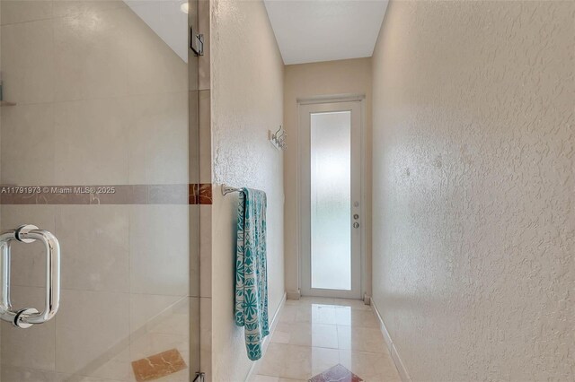 bathroom featuring a textured wall, tile patterned flooring, and baseboards