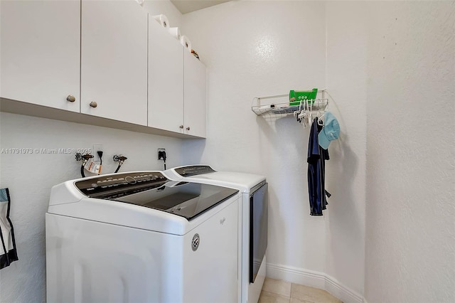 laundry room featuring light tile patterned flooring, cabinet space, baseboards, and washer and clothes dryer