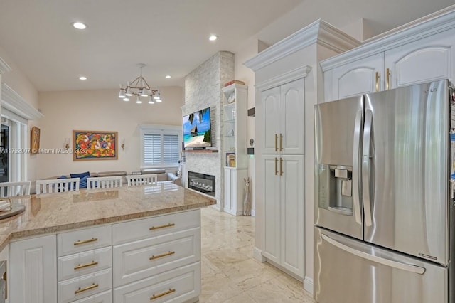19720 SW 79th Ct, Cutler Bay, FL 33189 - kitchen featuring a large fireplace, white cabinetry, stainless steel fridge with ice dispenser, and light stone counters