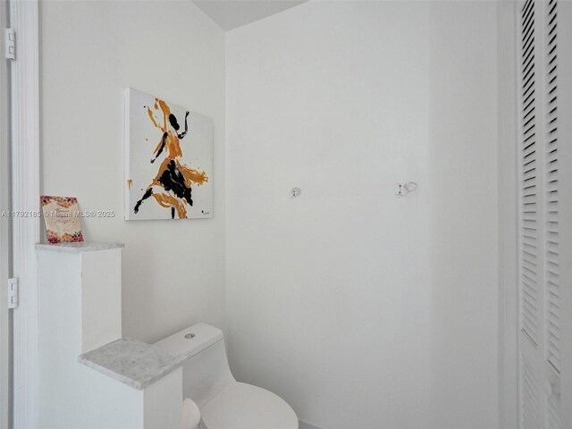 bathroom featuring toilet and a closet