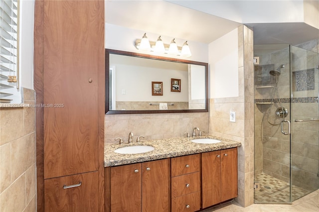 bathroom featuring double vanity, a sink, a shower stall, and tile walls