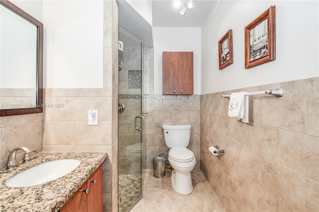 full bathroom featuring vanity, toilet, tile walls, tile patterned floors, and a stall shower
