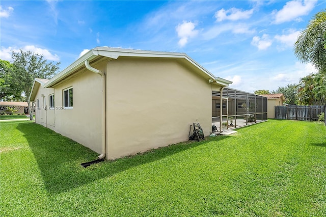 view of side of home featuring fence, a lanai, stucco siding, and a lawn