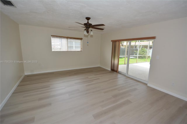 spare room featuring a healthy amount of sunlight, light wood-style floors, a ceiling fan, and visible vents