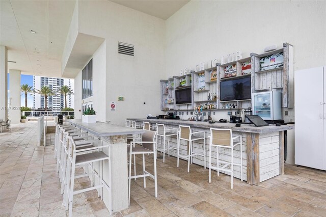 1830 S Ocean Dr Unit 1201, Hallandale Beach, FL 33009 - kitchen featuring a towering ceiling, freestanding refrigerator, open shelves, and a kitchen bar
