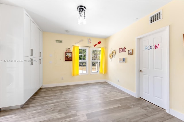 spare room with baseboards, visible vents, and light wood finished floors