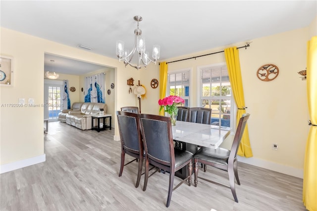 dining space featuring baseboards, light wood-type flooring, visible vents, and a notable chandelier