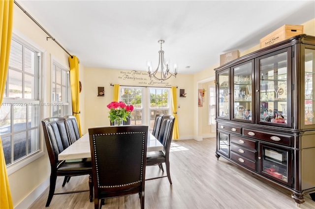 dining space featuring an inviting chandelier, light wood-style floors, and baseboards