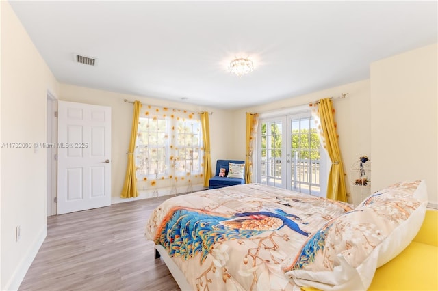 bedroom with wood finished floors, access to exterior, baseboards, visible vents, and french doors