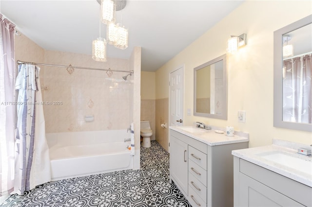 full bathroom with two vanities, shower / tub combo with curtain, toilet, and a sink
