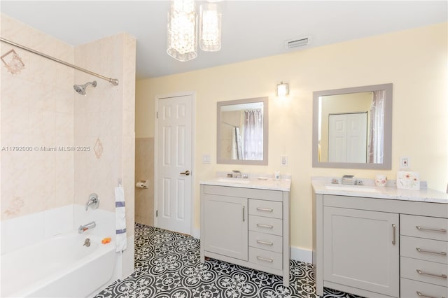 full bath featuring a sink, an inviting chandelier, shower / bath combination, two vanities, and visible vents