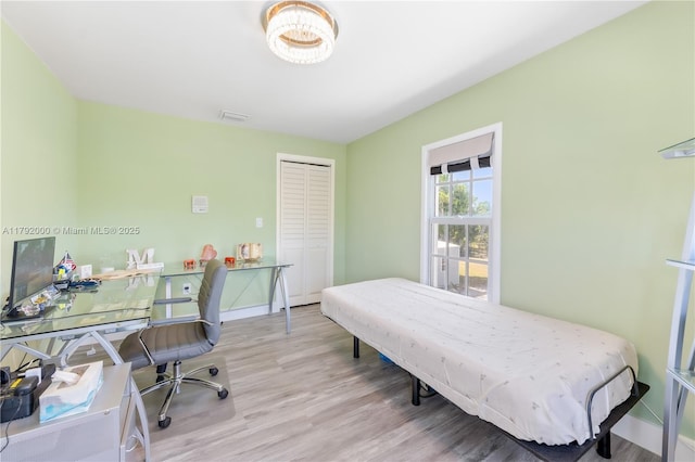 bedroom featuring wood finished floors, a closet, visible vents, and baseboards