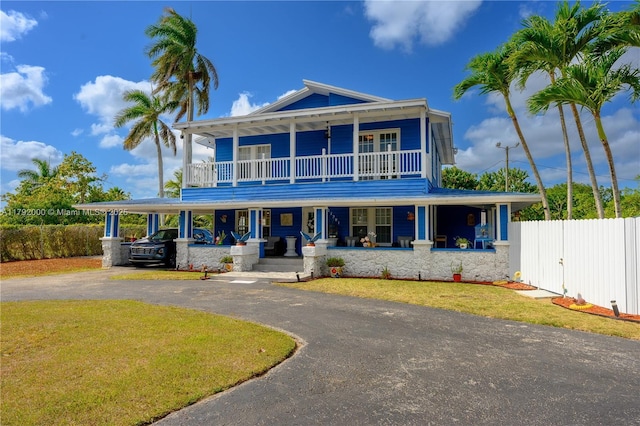 view of front facade with driveway, a carport, covered porch, a front yard, and fence