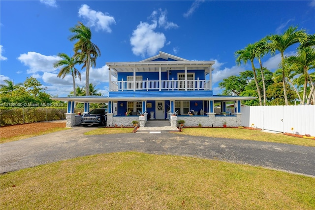 view of front of house with a porch, a front lawn, an attached carport, driveway, and fence