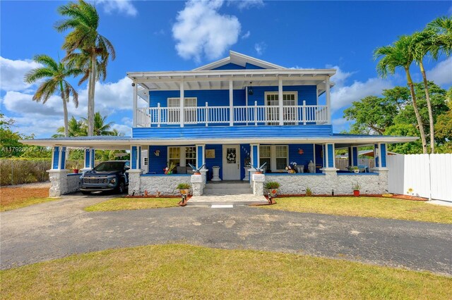 view of front of property with driveway, a carport, a balcony, covered porch, and fence