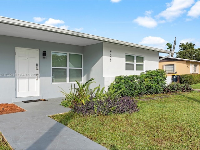view of front of house with stucco siding and a front lawn
