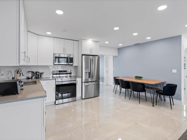 kitchen with white cabinets, a sink, appliances with stainless steel finishes, recessed lighting, and backsplash