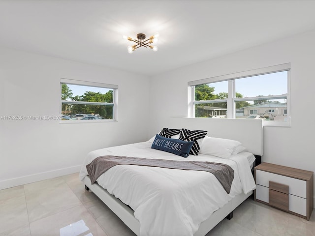 bedroom with multiple windows, a chandelier, and baseboards