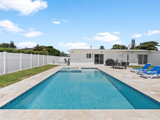 view of swimming pool with a grill, a pool with connected hot tub, a patio, and a fenced backyard