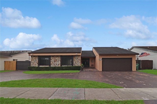 ranch-style house featuring a front yard, fence, curved driveway, an attached garage, and stone siding