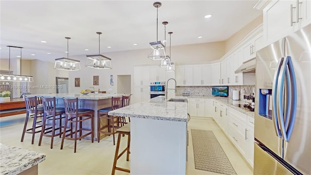 kitchen featuring white cabinets, a breakfast bar, stainless steel appliances, tasteful backsplash, and a spacious island