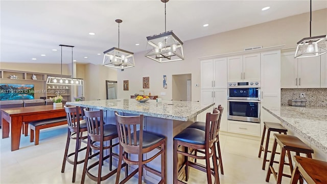 kitchen with decorative backsplash, a kitchen island, visible vents, white cabinets, and double oven