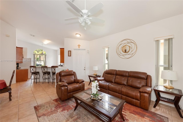 living area featuring lofted ceiling, light tile patterned floors, and ceiling fan
