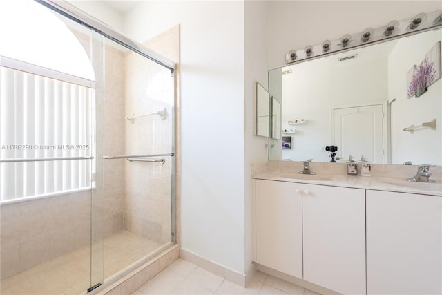 bathroom featuring tile patterned flooring, double vanity, a sink, and a shower stall