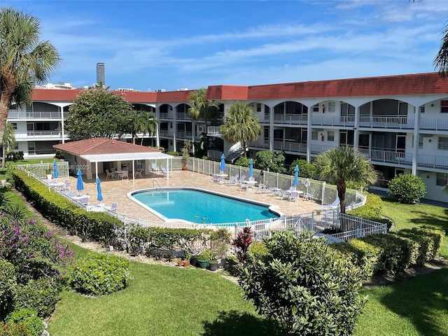 pool with fence, a lawn, and a patio