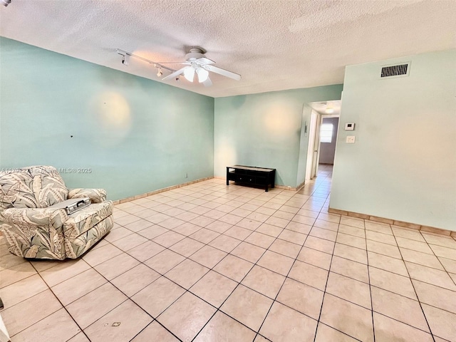 unfurnished living room with light tile patterned floors, ceiling fan, baseboards, visible vents, and a textured ceiling