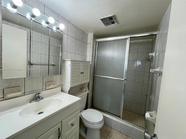 bathroom with a stall shower, tile walls, visible vents, and vanity