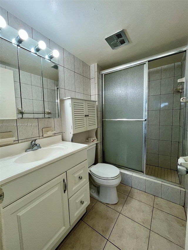 full bathroom featuring tile patterned floors, tile walls, toilet, visible vents, and a stall shower