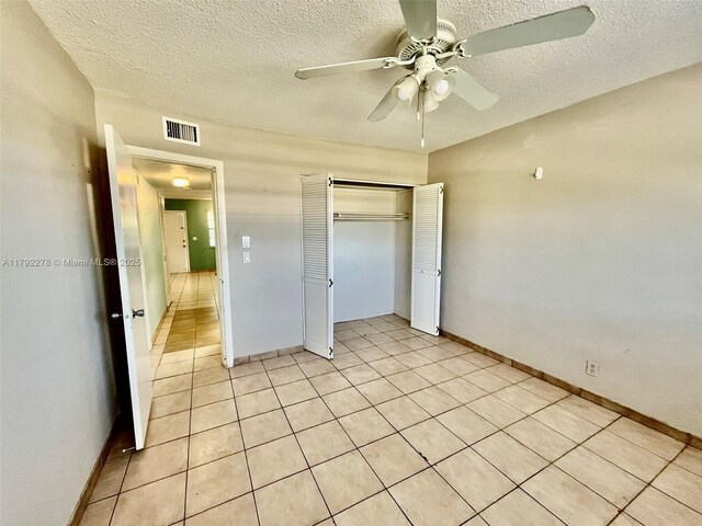 unfurnished bedroom featuring light tile patterned floors, a closet, baseboards, visible vents, and a textured ceiling