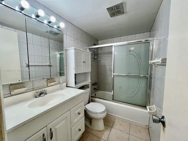 full bath featuring vanity, tile patterned floors, toilet, combined bath / shower with glass door, and visible vents