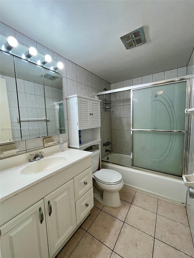 full bath featuring vanity, toilet, combined bath / shower with glass door, visible vents, and tile patterned flooring